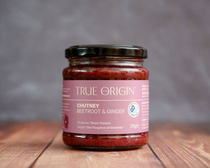 Jar of True Origin chutney on a wooden surface with a gray background