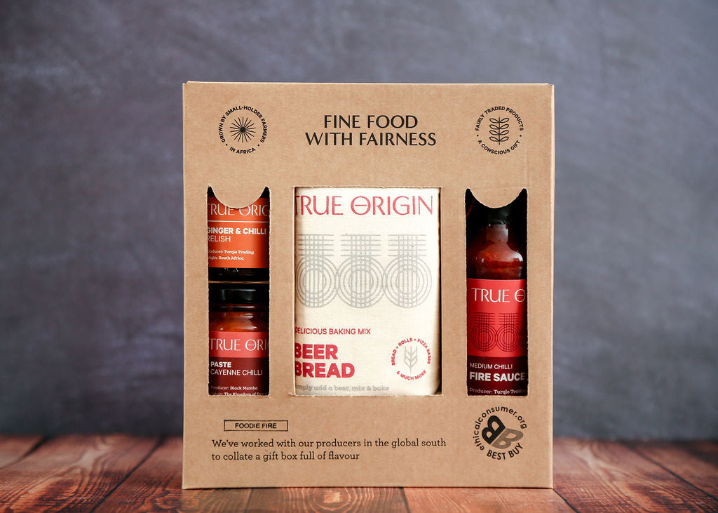 Gift set with True Origin products in a cardboard box on a wooden surface with a gray background