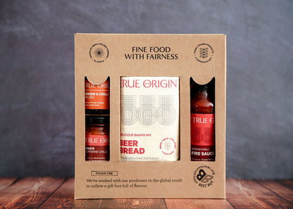 Gift set with True Origin products in a cardboard box on a wooden surface with a gray background