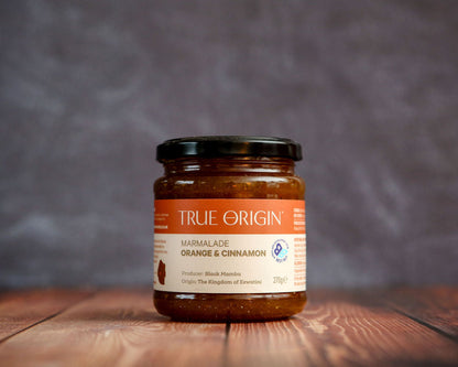 Jar of True Origin marmalade on a wooden surface with a blurred background